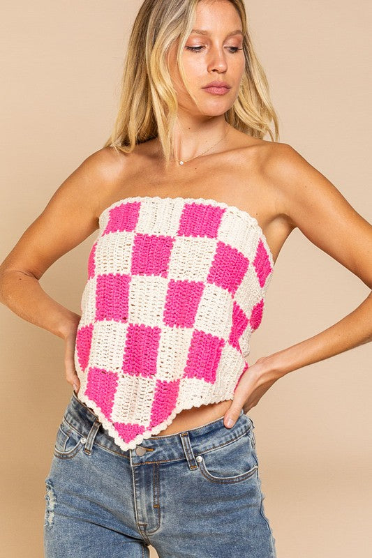 A woman stands against a beige background, wearing the playful Checkerboard Pattern Tube Top Sweater in pink and white, which beautifully contrasts with her blue jeans.