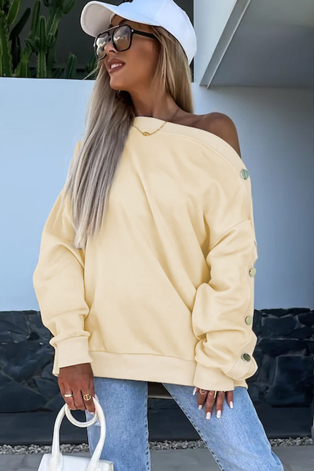 Woman with long wavy hair wearing the Beige Buttoned Sleeve Dropped Shoulder Sweatshirt, standing in a bright indoor setting.
