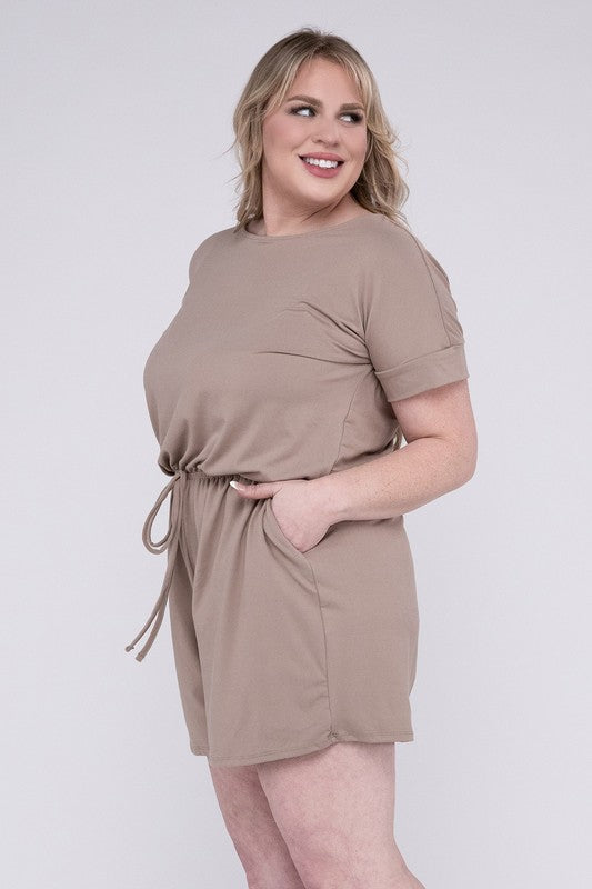 A person is wearing the Plus Brushed DTY Romper with Pockets in bright pink, smiling as they pose with one hand on their head and the other tucked into a pocket, all set against a gray background.