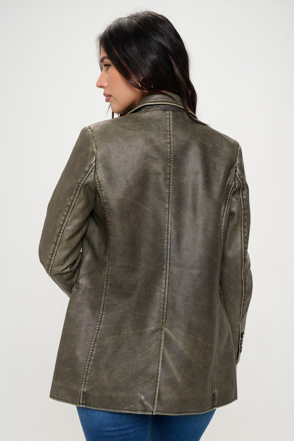 A person with long dark hair wears the Coalition LA Single-Breasted Vegan Leather Blazer in olive green over a black crop top and blue jeans against a neutral background, showcasing a stylish and ethical fashion choice.