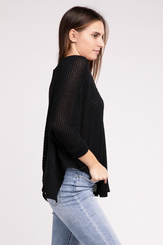 A woman in a 3/4 Sleeve V-Neck Hi-Low Hem Jacquard Sweater and black jeans, posing with one arm raised, eyes closed, against a light gray background.