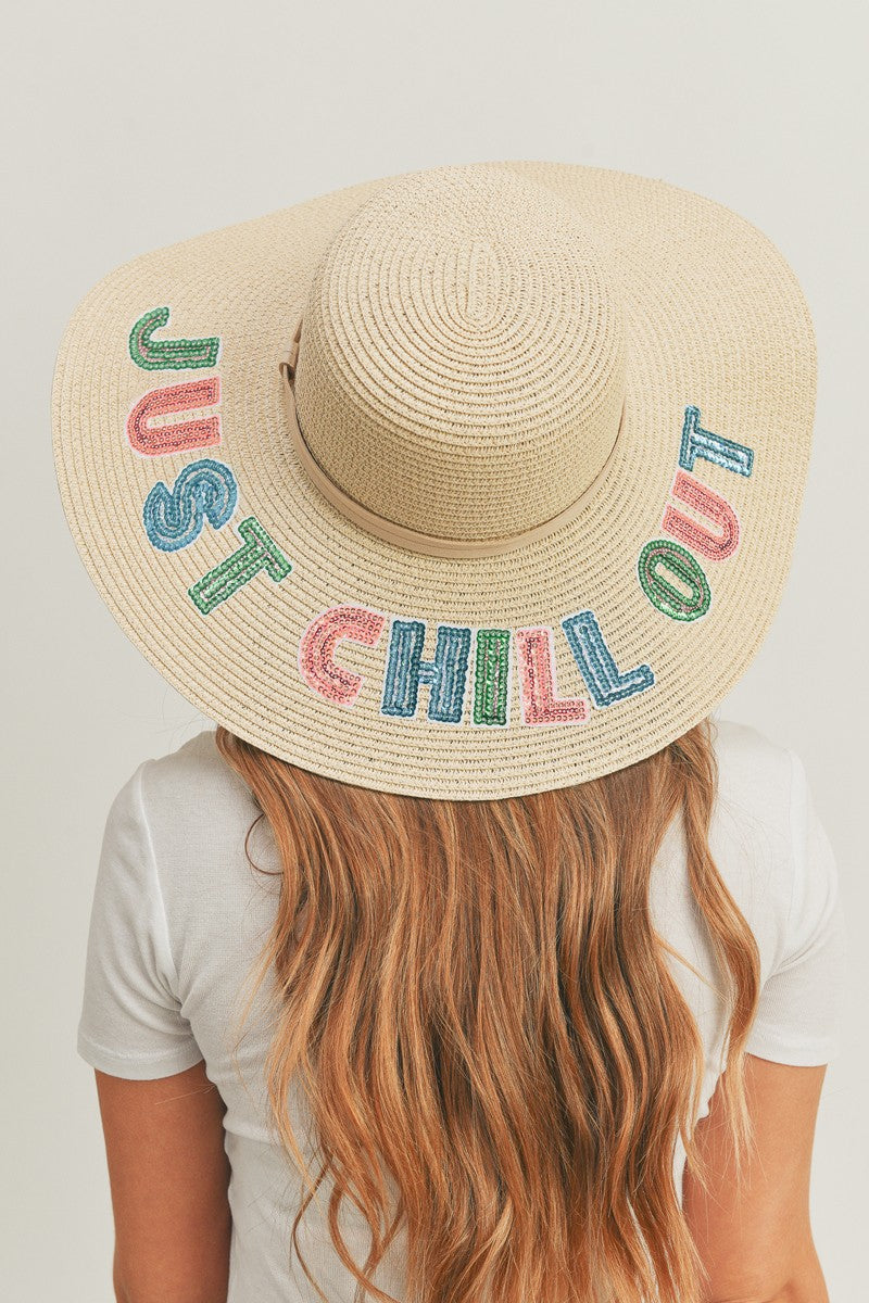 Wearing the Fame Sequin Letter Graphic Wide Brim Straw Hat, a person with long hair embraces a summer look, featuring the colorful sequin letters "JUST CHILL OUT.