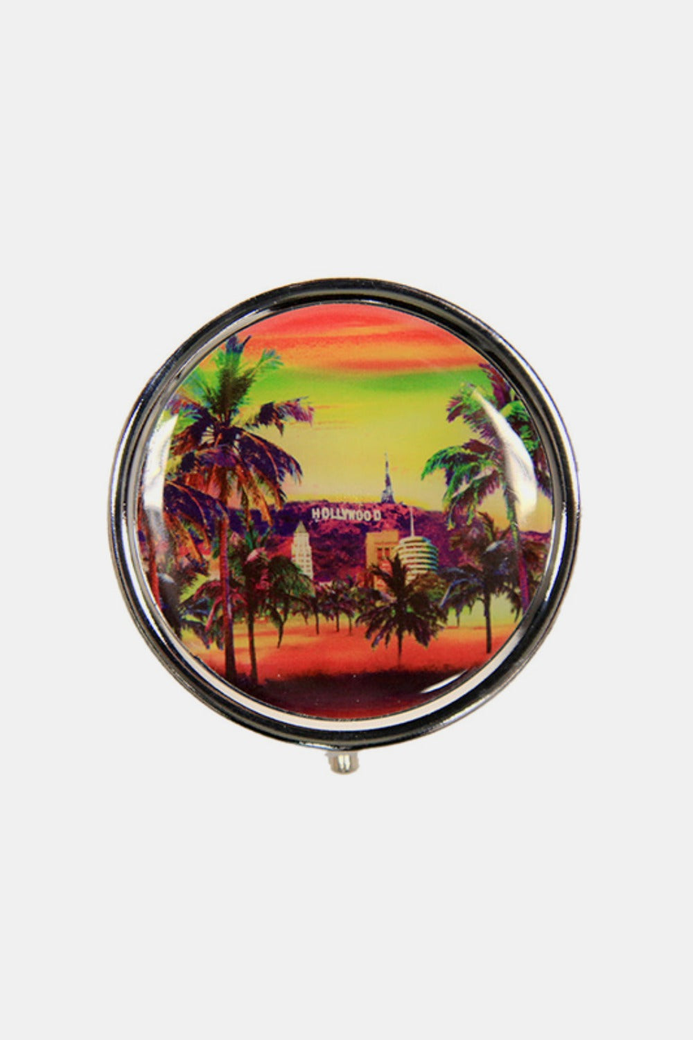 The Nicole Lee USA Print Metallic Circular Small Pill Case holds a metal pin that showcases an illustration of a dog and cat driving a red convertible through a city adorned with iconic buildings and landmarks, all wrapped in a sleek silver-tone metal exterior.