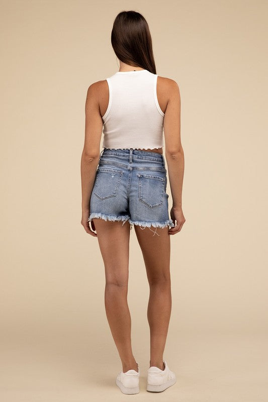 Individual wearing Mid Rise Raw Frayed Hem Denim Shorts paired with a white cropped top.