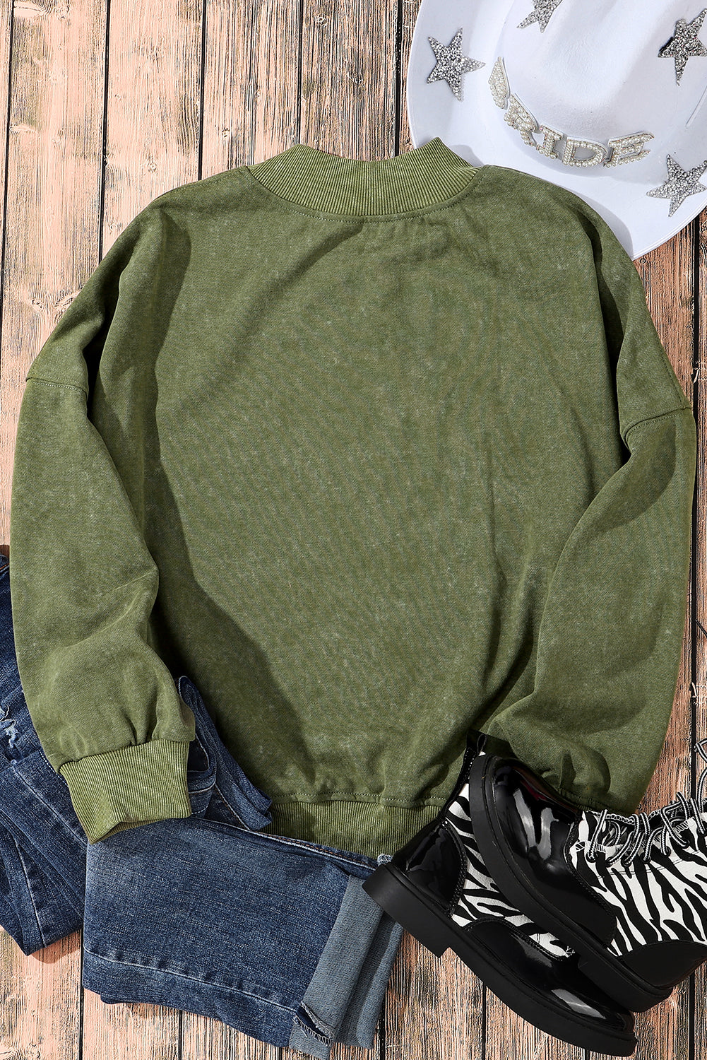 Person wearing a Green Drop Shoulder Crew Neck Pullover Sweatshirt with rolled-up sleeves, grey jeans, and bracelets. Their hand is in their pocket.