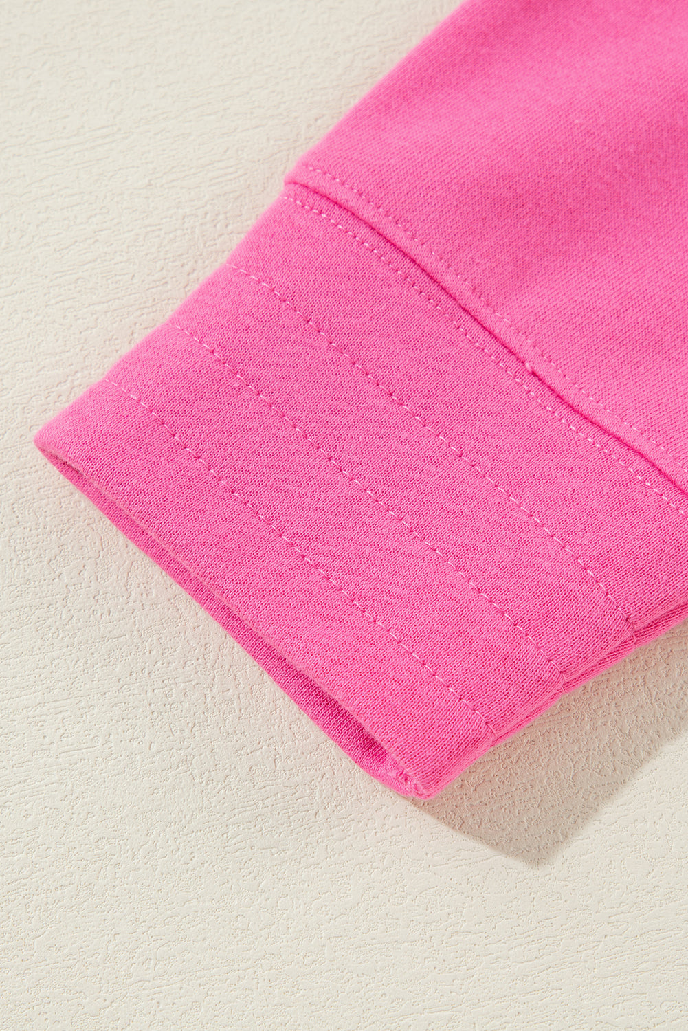 A person with long hair is seen from behind, wearing a Bright Pink Vintage Mineral Wash Half Button Collared Sweatshirt and light blue jeans.