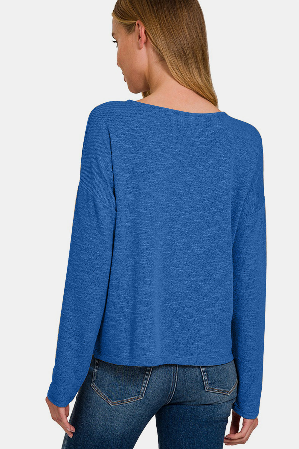 A person wearing a Zenana Dropped Shoulder Long Sleeve T-Shirt in blue and jeans stands against a plain background.