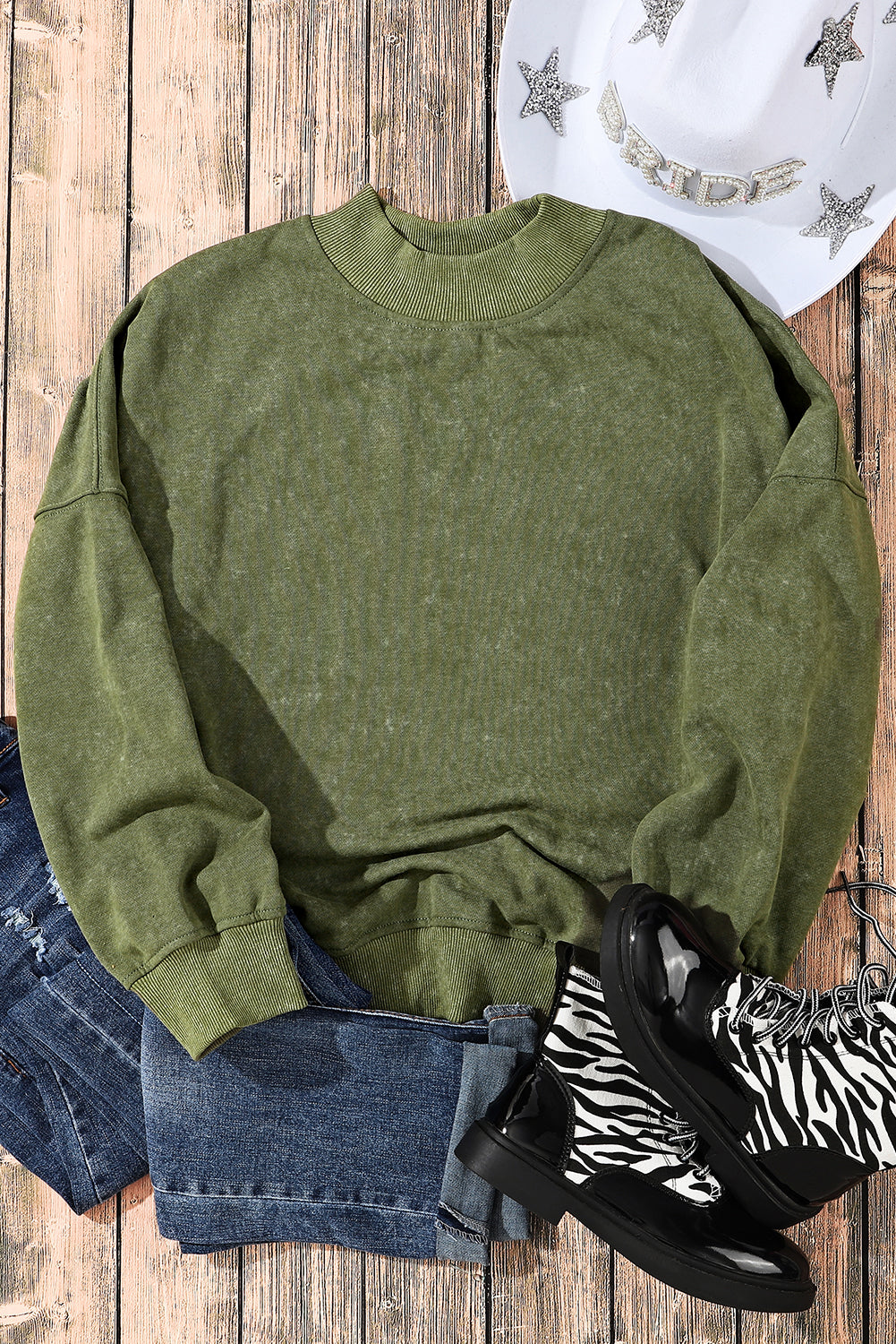 Person wearing a Green Drop Shoulder Crew Neck Pullover Sweatshirt with rolled-up sleeves, grey jeans, and bracelets. Their hand is in their pocket.