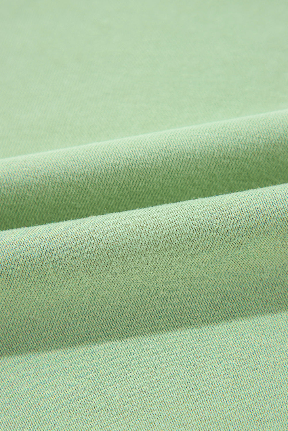 A person with long hair, seen from the back, wearing a Grass Green Solid Fleece Lined Drop Shoulder High Low Sweatshirt and black pants.