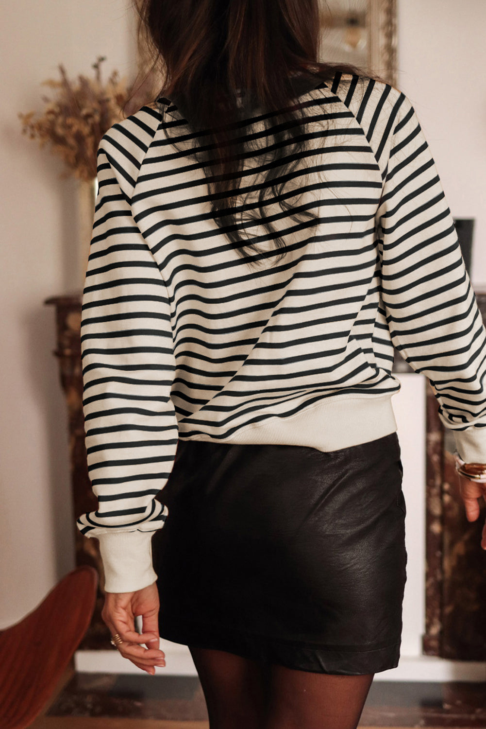 A person with long hair is facing away, wearing a Black Stripe CIAO AMORE Graphic Buttoned Pullover Sweatshirt and a black skirt in an indoor setting. The shirt subtly whispers "CIAO AMORE.