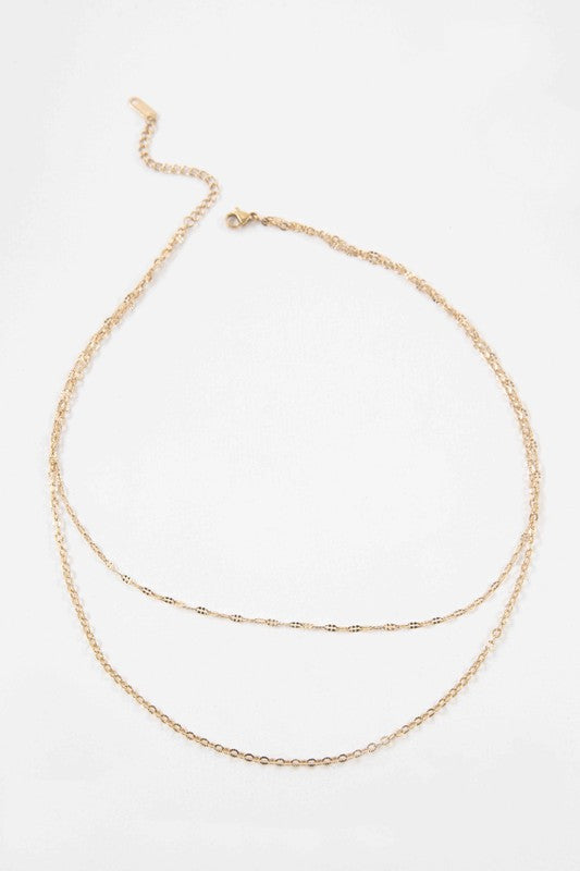 The Othello Layered Necklace is a refined piece crafted from 14k gold-plated stainless steel, featuring a double-layered chain design with a lobster clasp and adjustable length.