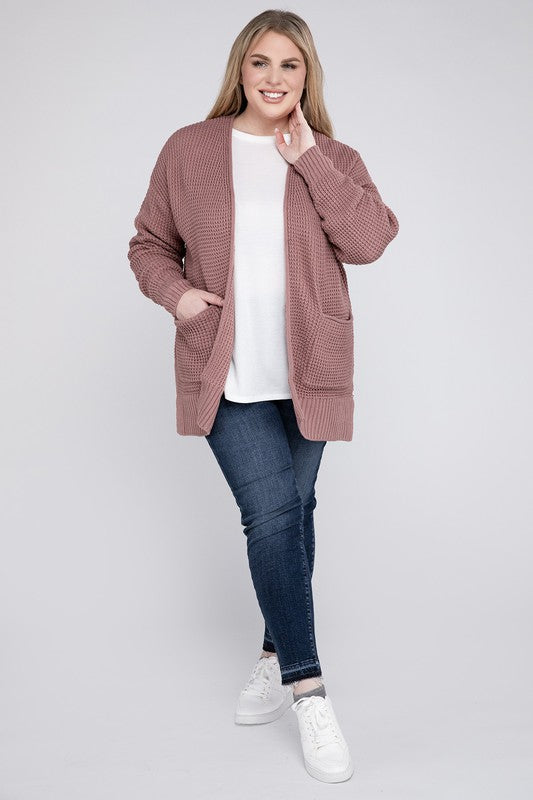 A woman in a white top and oversized dusty rose Plus Low Gauge Waffle Open Cardigan Sweater standing with hands in pockets, looking at the camera.
