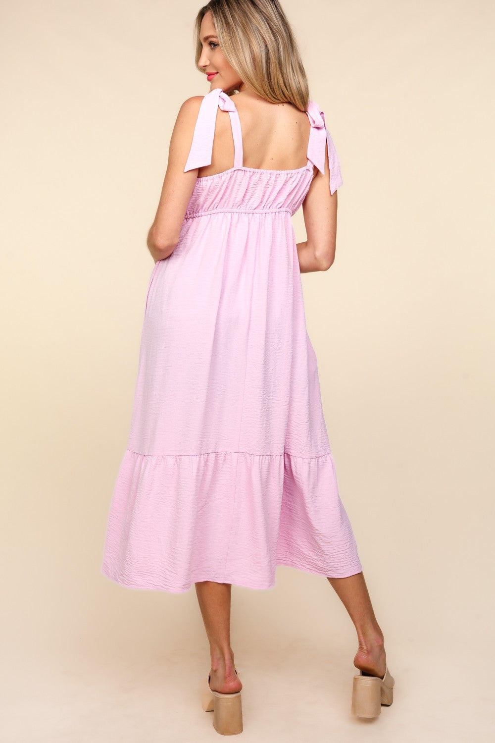 A woman in the Haptics Crochet Lace Ruffle Hem Cami Midi Dress poses against a beige background. She wears neutral-colored platform sandals.