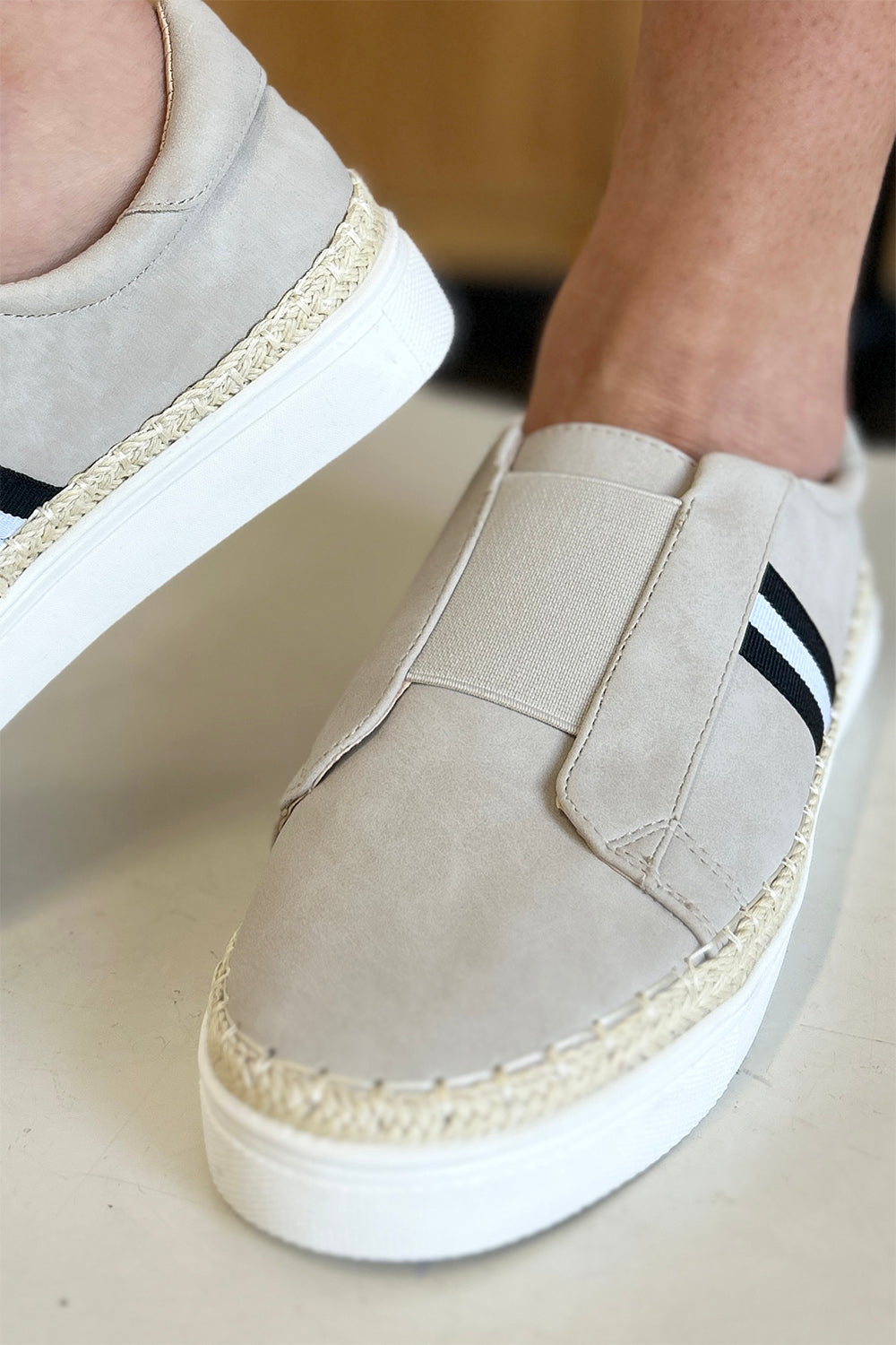 A person wearing the chic CCOCCI Striped Round Neck Sneakers in beige, featuring black and white stripes on a light surface, ideal for everyday wear.