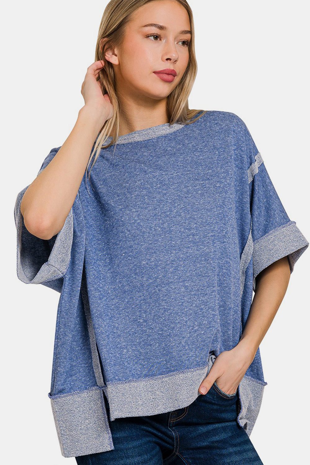 A smiling woman with light blonde hair is wearing a Zenana Contrast Trim Drop Shoulder T-Shirt, featuring grey contrast trim on the sleeves and hem, paired with casual blue jeans.