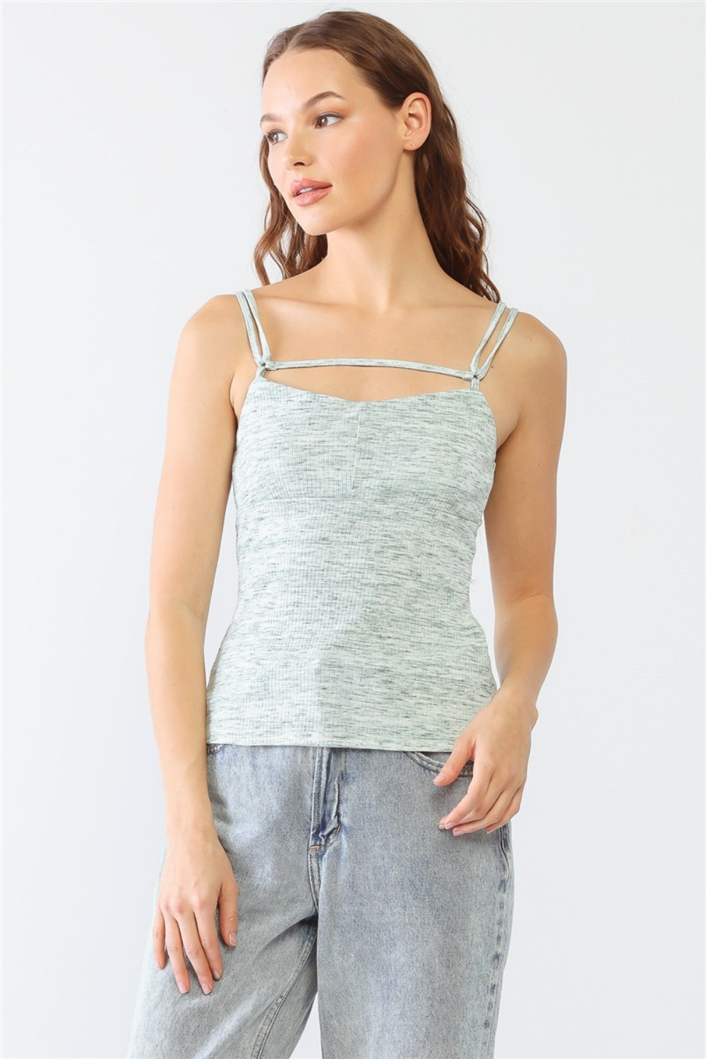 Dressed in a stylish Le Lis Heathered Ribbed Adjustable Strap Cami, a person stands against a plain background, paired with jeans.