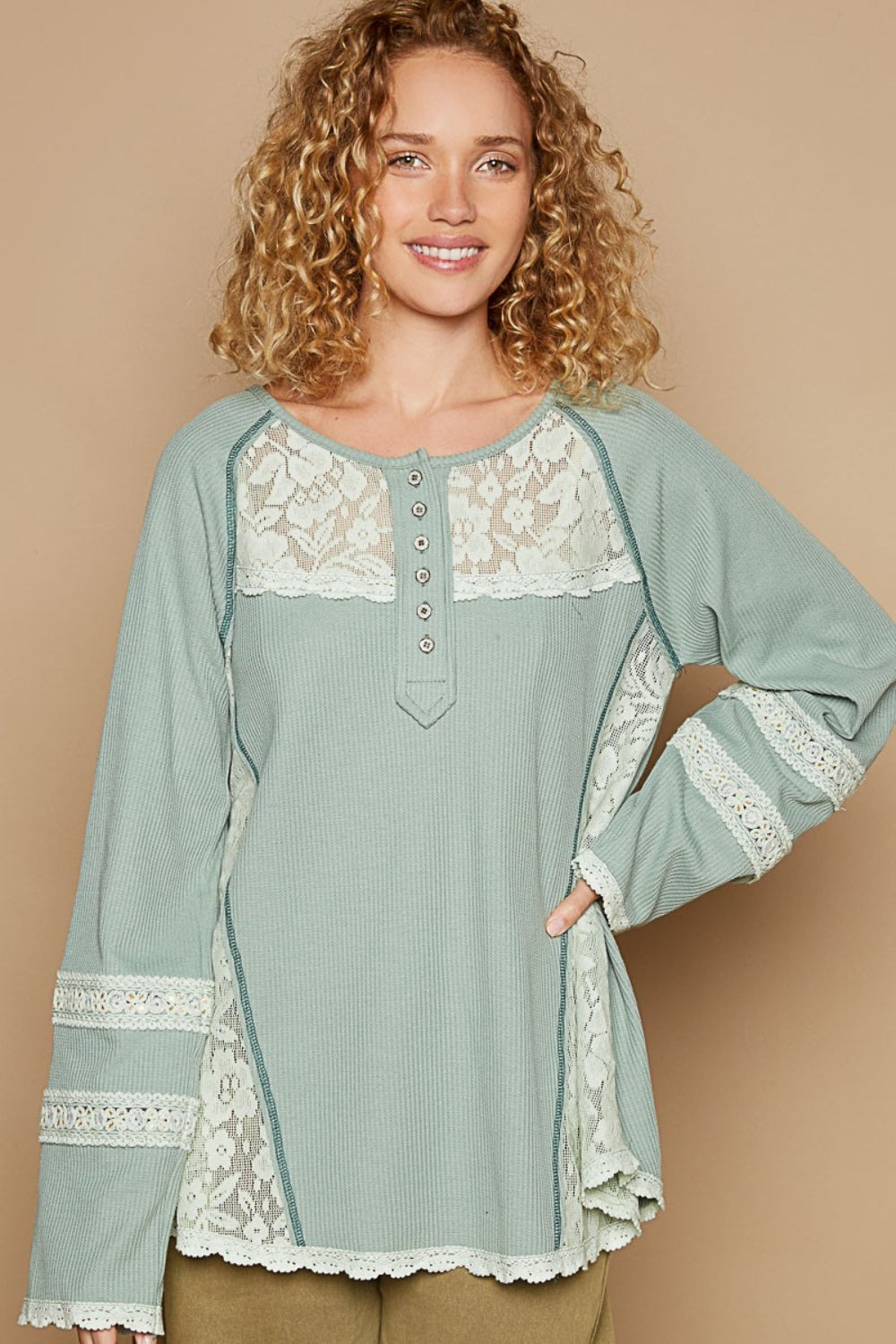 A woman with curly hair wears a pastel green POL Round Neck Long Sleeve Lace Trim Thermal Top with buttons on the front, standing against a plain beige background.