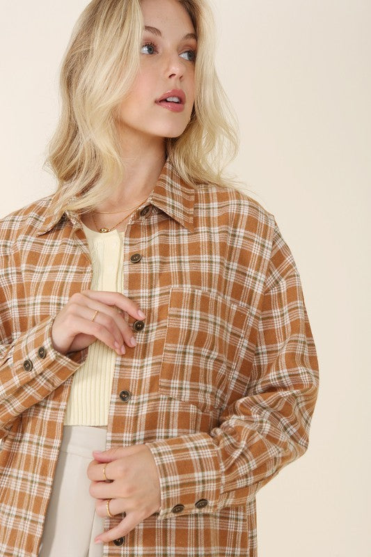 Wearing an Autumn beige plaid shirt, a person with long hair complements their look with hoop earrings, showcasing the season's warm hues. This long-sleeved shirt rests gracefully against a beige backdrop and is ideal for machine wash cold care.