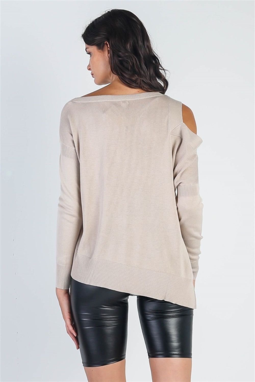 A person wearing the UNIQ Cold Shoulder Long Sleeve Knit Top in black and distressed denim shorts stands against a plain white background, effortlessly showcasing a versatile wardrobe choice.