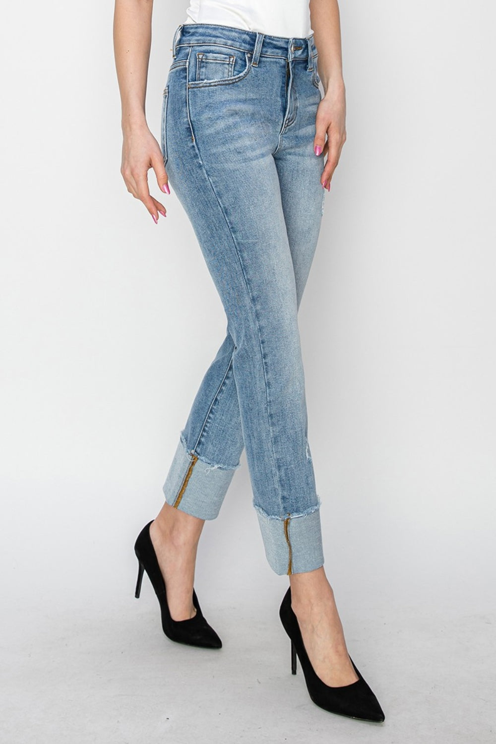 A person wearing RISEN Full Size High Rise Cuffed Slim Straight Jeans and black high heels stands against a white background.