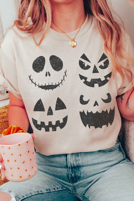 A person wears the SCARY PUMPKINS Graphic Tee, featuring four black, scary pumpkin faces, paired with checkered shorts.