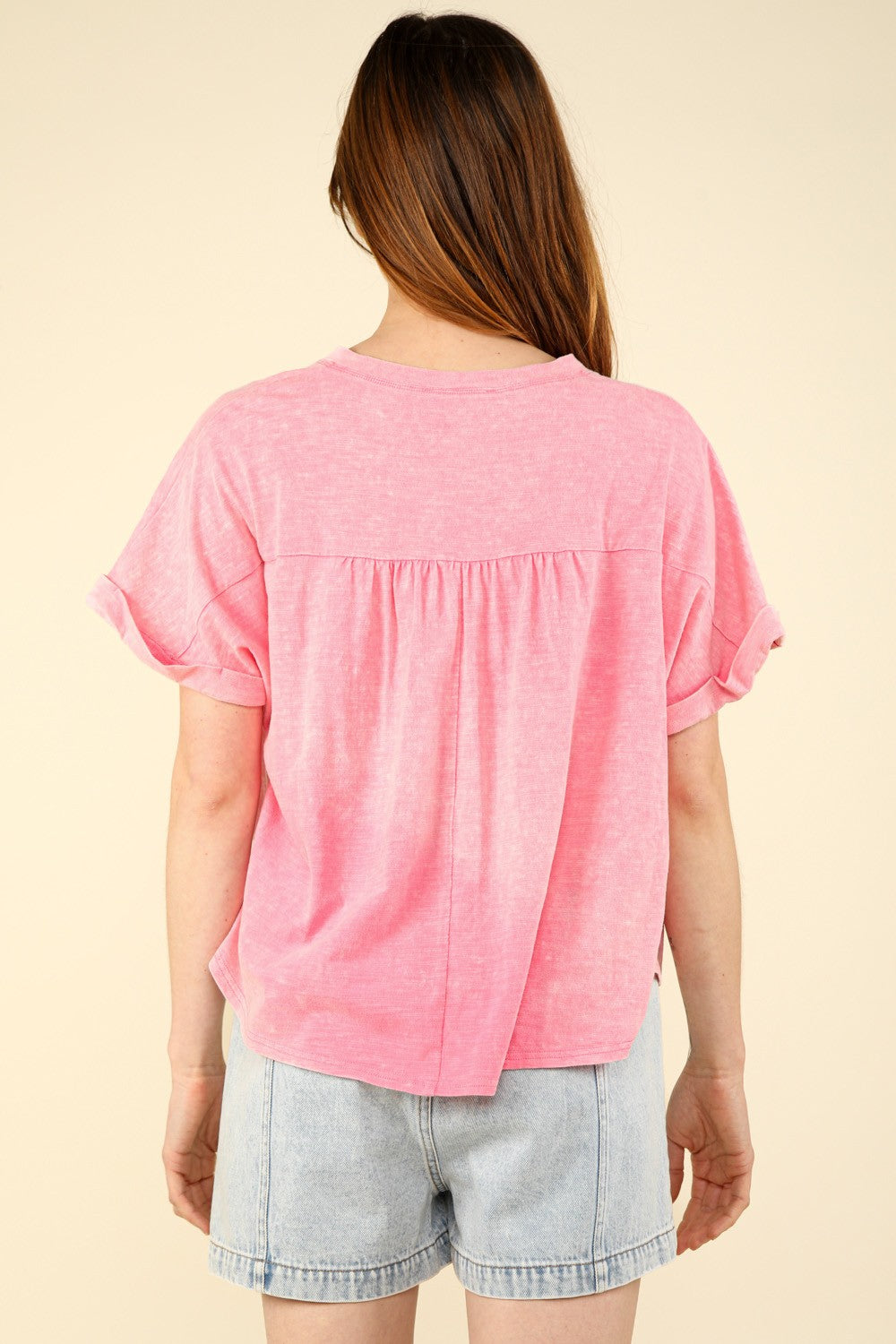 A woman in a casual fit with a VERY J Notched Short Sleeve Washed T-Shirt and light denim shorts stands against a plain background, capturing the essence of everyday wear.