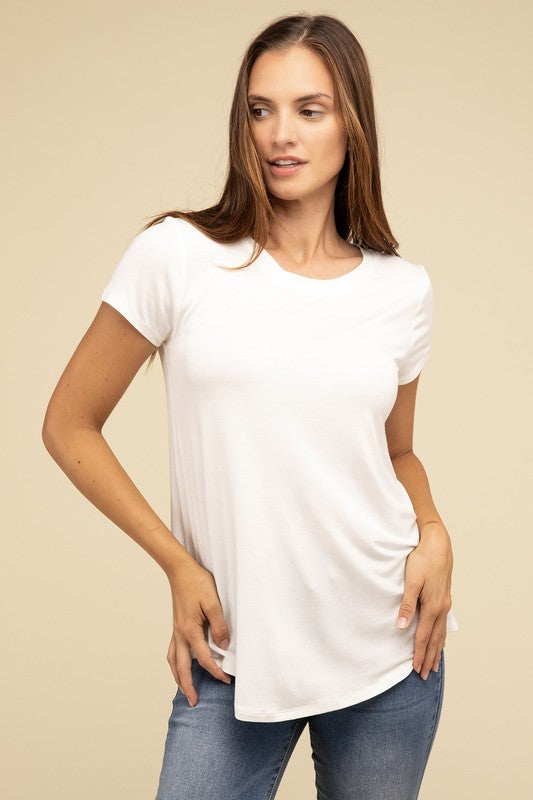 A person with long hair is wearing a blue Flowy Round Hem Rayon Short Sleeve Top and black pants, standing against a plain beige background.