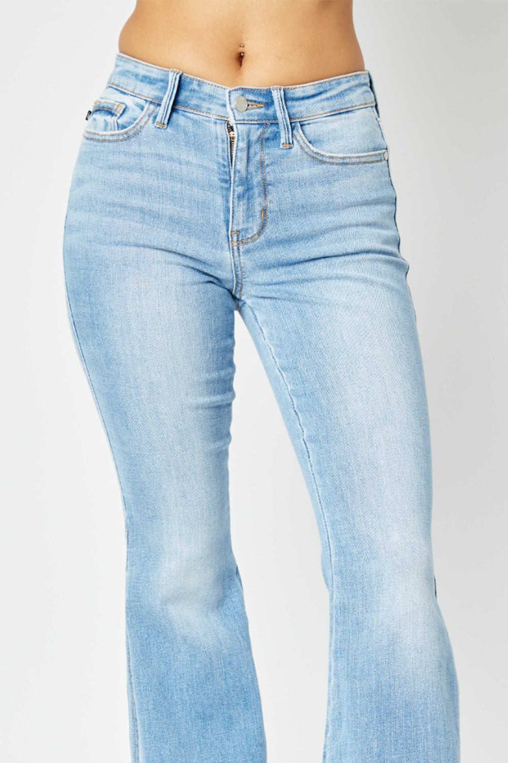 A person is wearing Judy Blue Full Size Mid Rise Raw Hem Slit Flare Jeans with a flattering silhouette and black open-toe shoes.