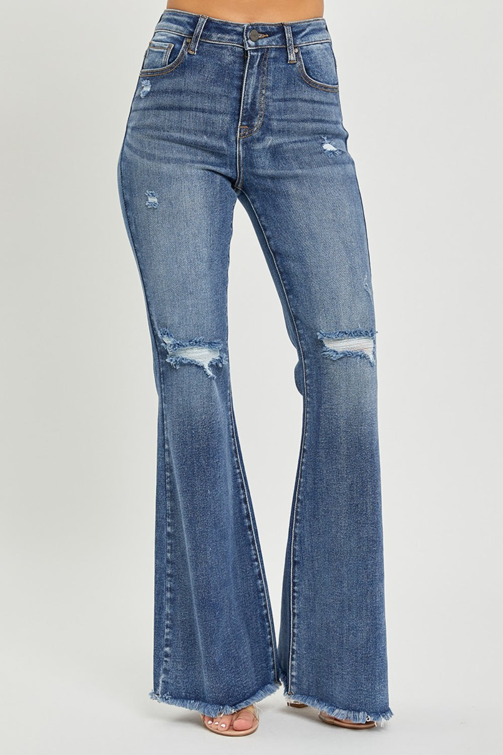 A person is wearing RISEN High Waist Distressed Fare Jeans, characterized by a high-waisted fit with minor rips and frayed hems, standing against a neutral background.