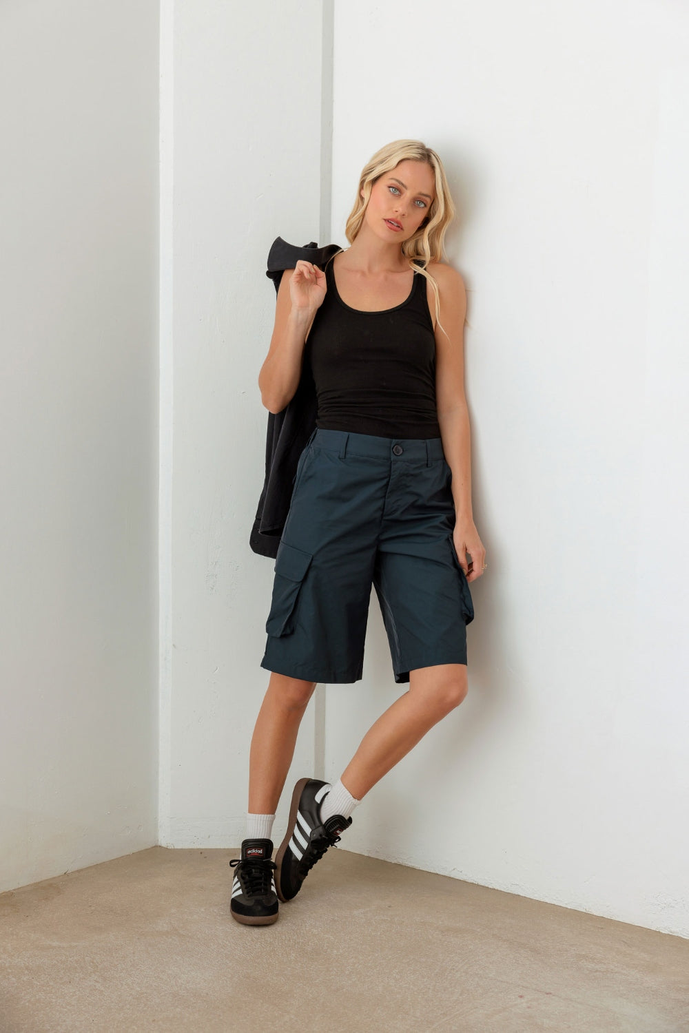 Person wearing a black sleeveless top and Le Lis Navy Cargo Bermuda Shorts with pockets, perfect for a warm-weather wardrobe.