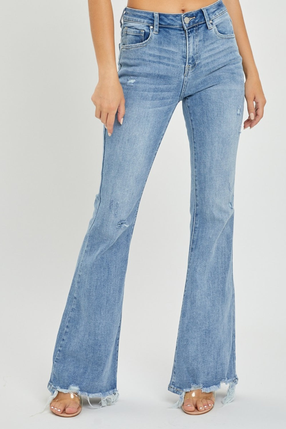 A person wearing the Risen Full Size High Rise Frayed Hem Flare Jeans in light blue with distressed details.