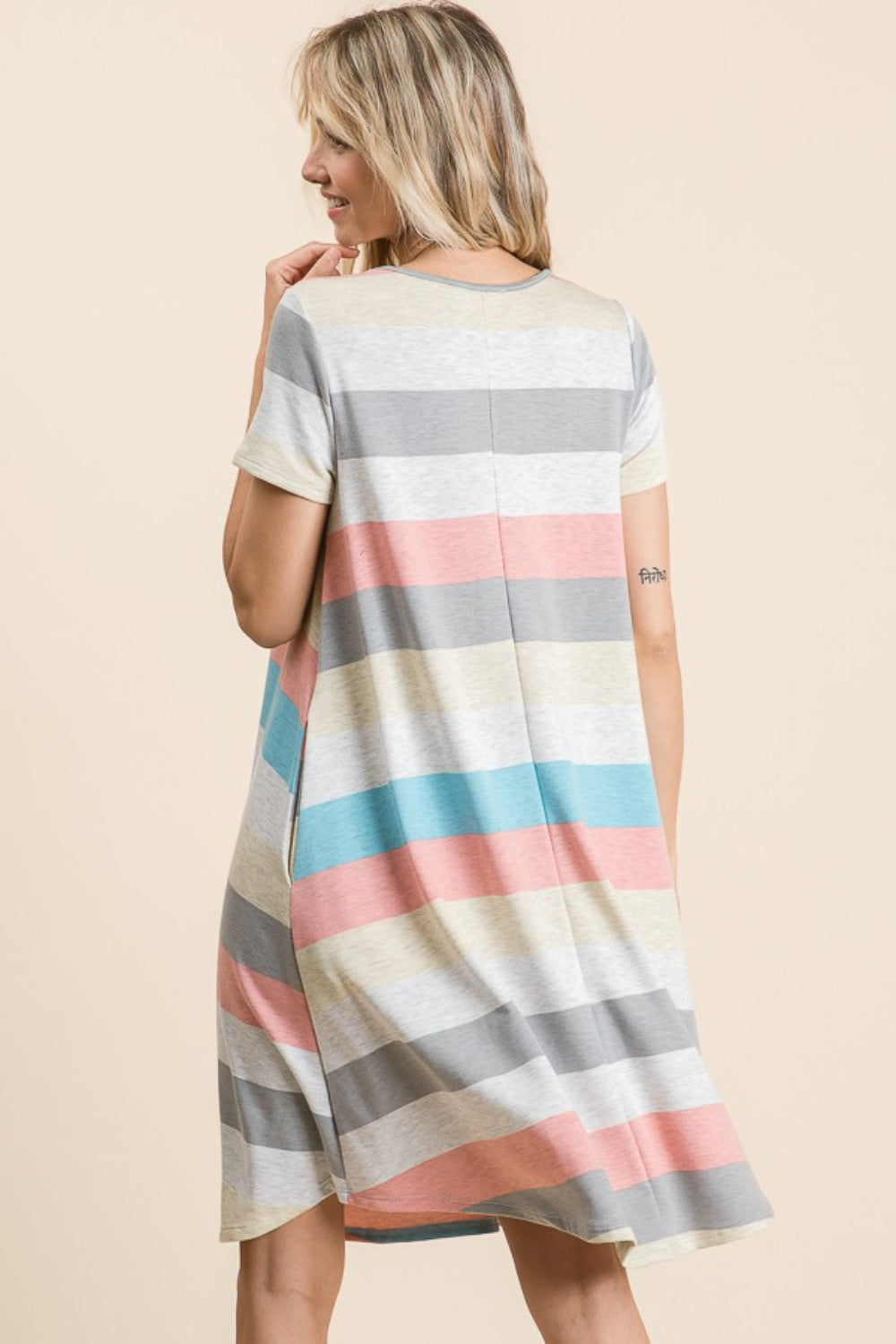 A woman is wearing the BOMBOM Striped Short Sleeve Dress, showcasing multicolored patterns and practical pockets for a casual look.