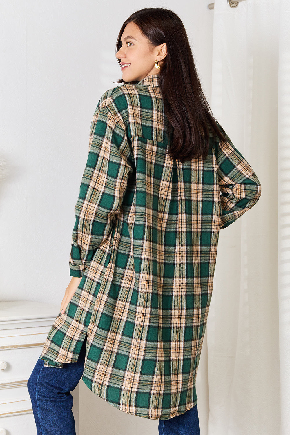 A person wearing the Mandy Plaid Collared Neck Long Sleeve Shirt in green and beige over a white crop top and blue jeans, standing indoors near a white dresser with vases.