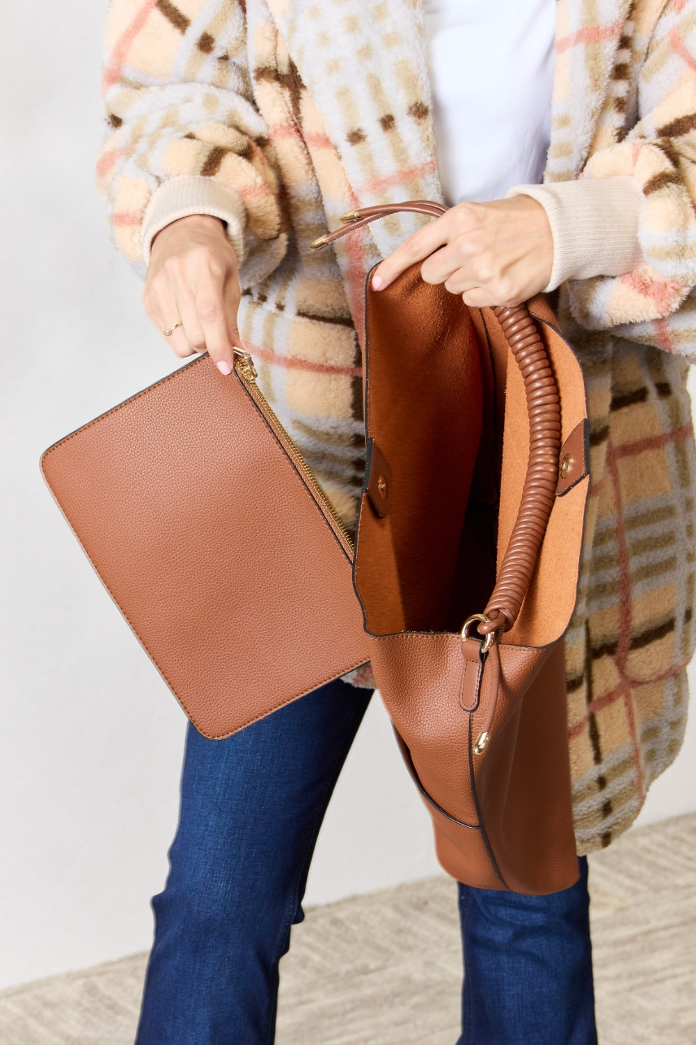 Person carrying a SHOMICO Vegan Leather Handbag with a front pocket and coiled handles, showcasing both versatility and durability.