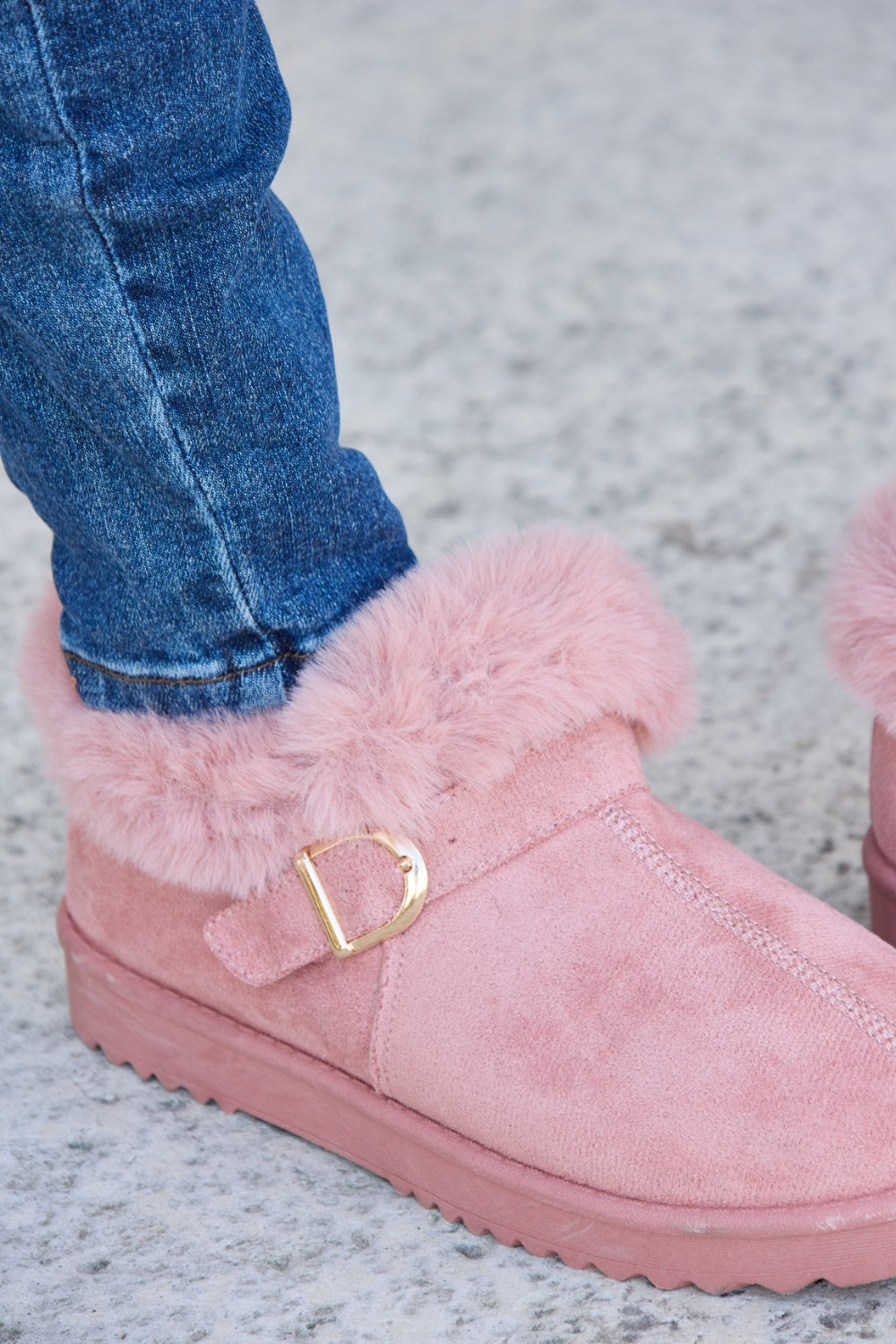 A person stands on a concrete surface, sporting ripped blue jeans and the Forever Link Furry Chunky Thermal Ankle Boots. The furry lining of these fashionable boots suggests both comfort and warmth for winter.