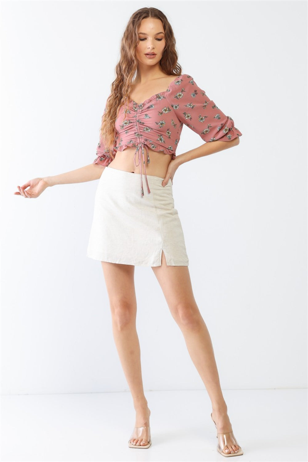 Person wearing the Miss Love / Kevin Co. Floral Ruffle Smocked Back Ruched Crop Top in pink, paired with a cream skirt, posing gracefully against a neutral background.