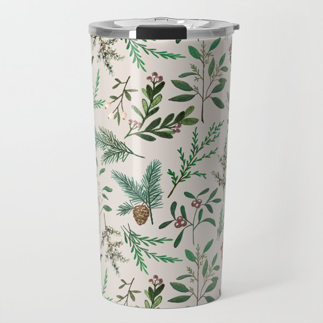 Introducing the Winter Berry Travel Mug: a tall, double-walled tumbler with a stainless steel interior. It showcases an elegant botanical leaf and pinecone design on a light backdrop. Resting serenely on a marble surface, it effortlessly blends into the blurred coziness of its surroundings. Ideal for travel mug enthusiasts who value both style and functionality.