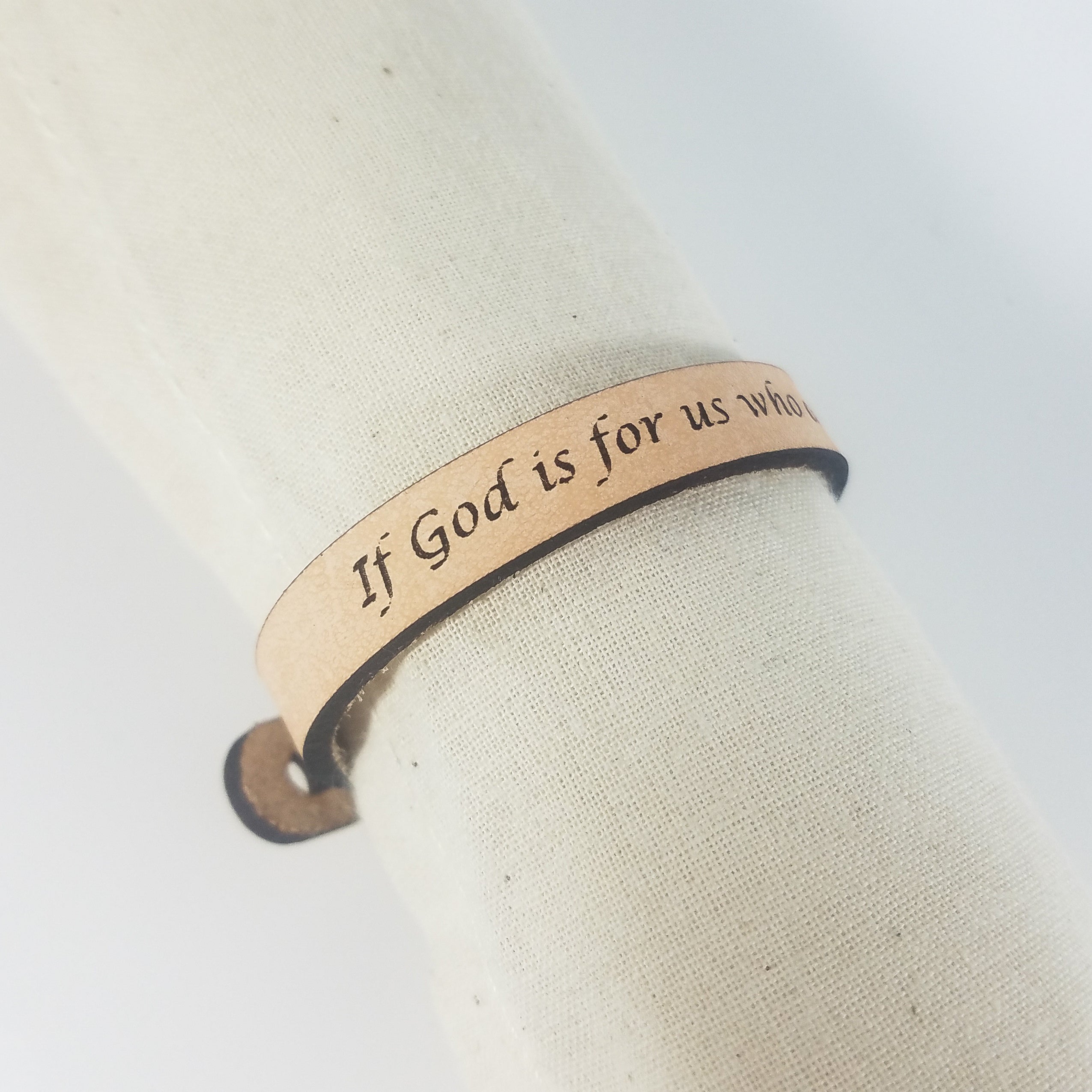 The Spiritual Quote Bracelet made of genuine leather features an adjustable button closure and is inscribed with the message: "If God is for us, who can be against us.