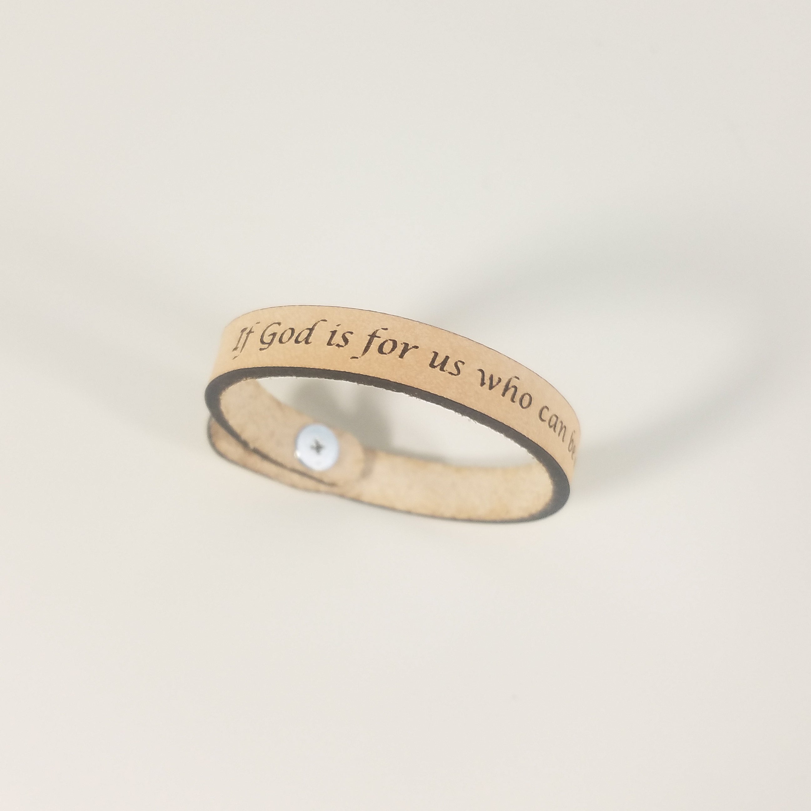 The Spiritual Quote Bracelet made of genuine leather features an adjustable button closure and is inscribed with the message: "If God is for us, who can be against us.