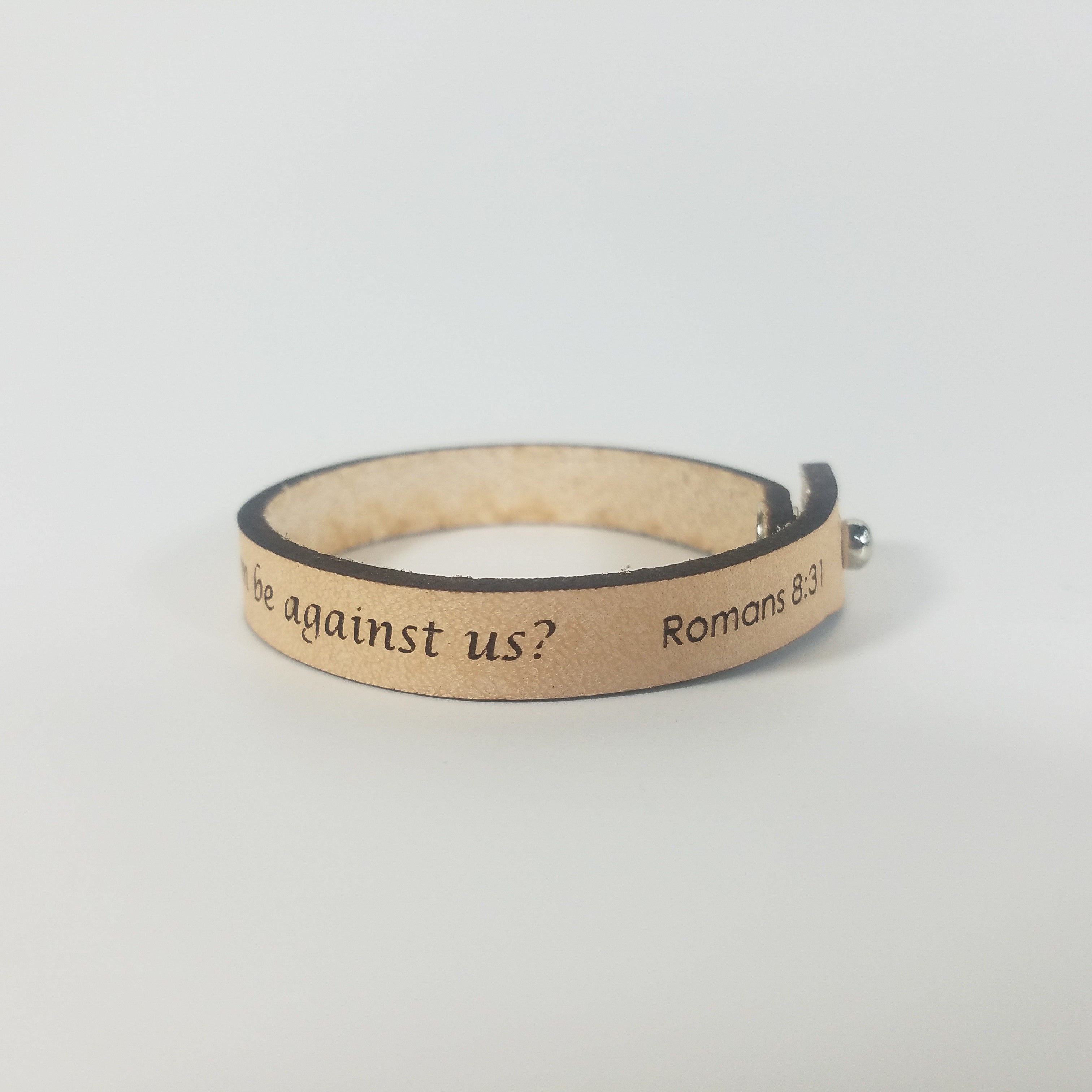 The Spiritual Quote Bracelet made of genuine leather features an adjustable button closure and is inscribed with the message: "If God is for us, who can be against us.