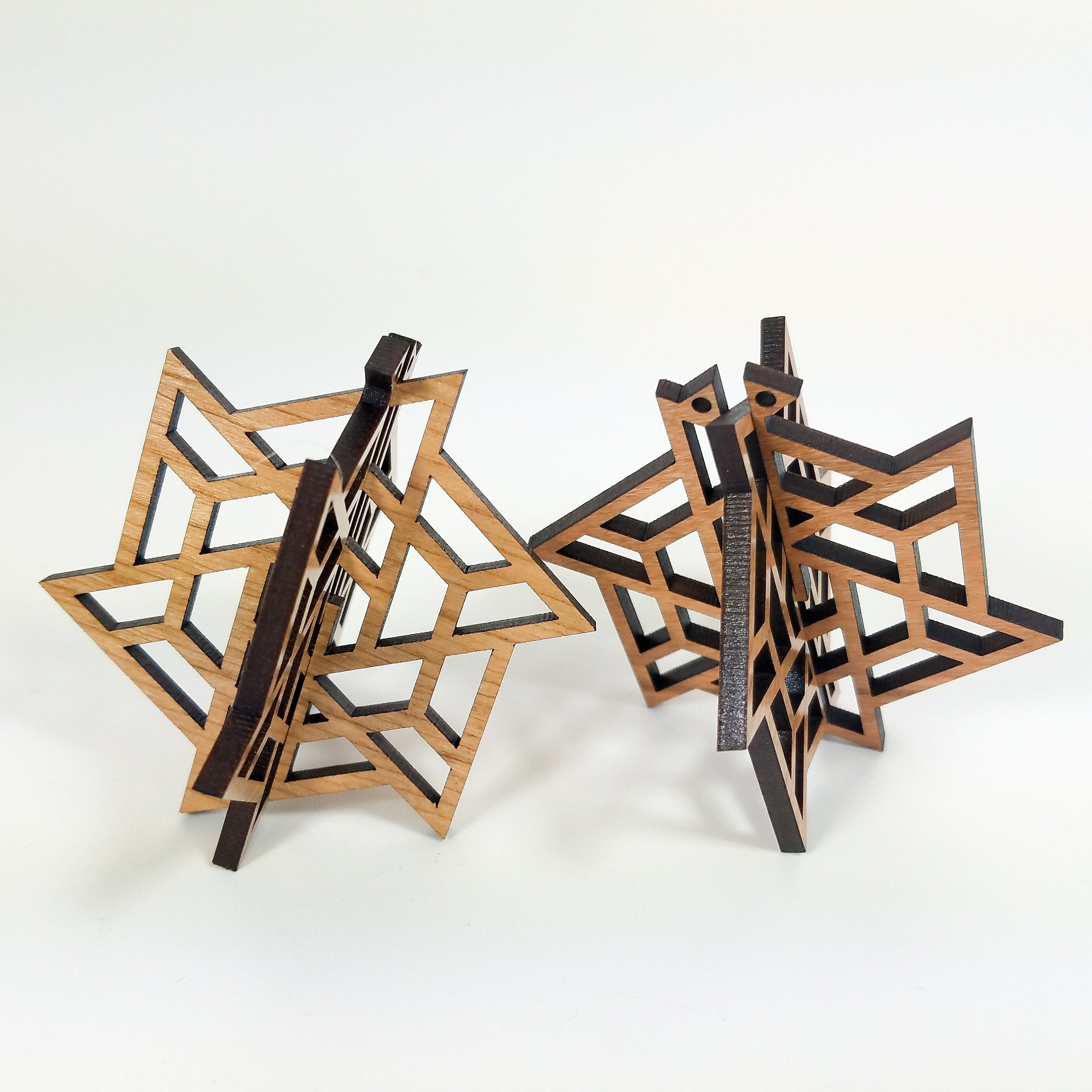 Three intricately carved Wood Christmas Ornaments hang from black ribbons against a white background, showcasing a modern ornament design.