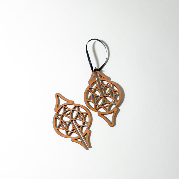 Three intricately carved Wood Christmas Ornaments hang from black ribbons against a white background, showcasing a modern ornament design.