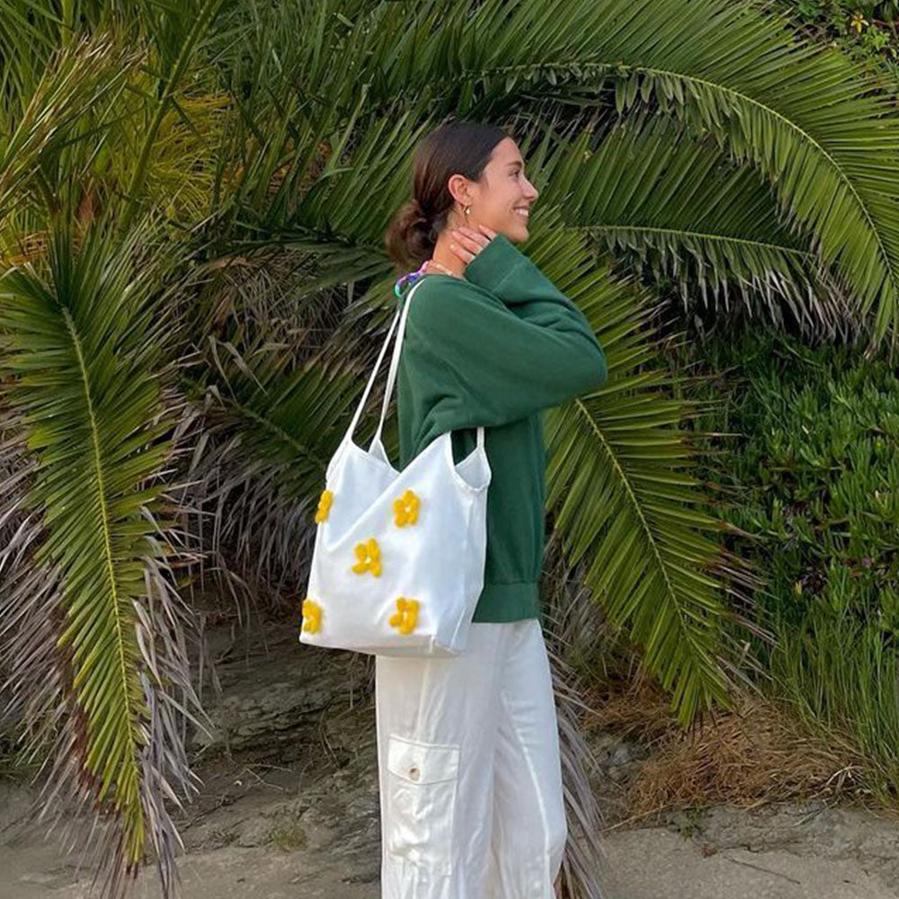 The Lily Canvas Shopper Tote is an eco-friendly cotton canvas bag featuring exquisite purple flower embroidery on the front.