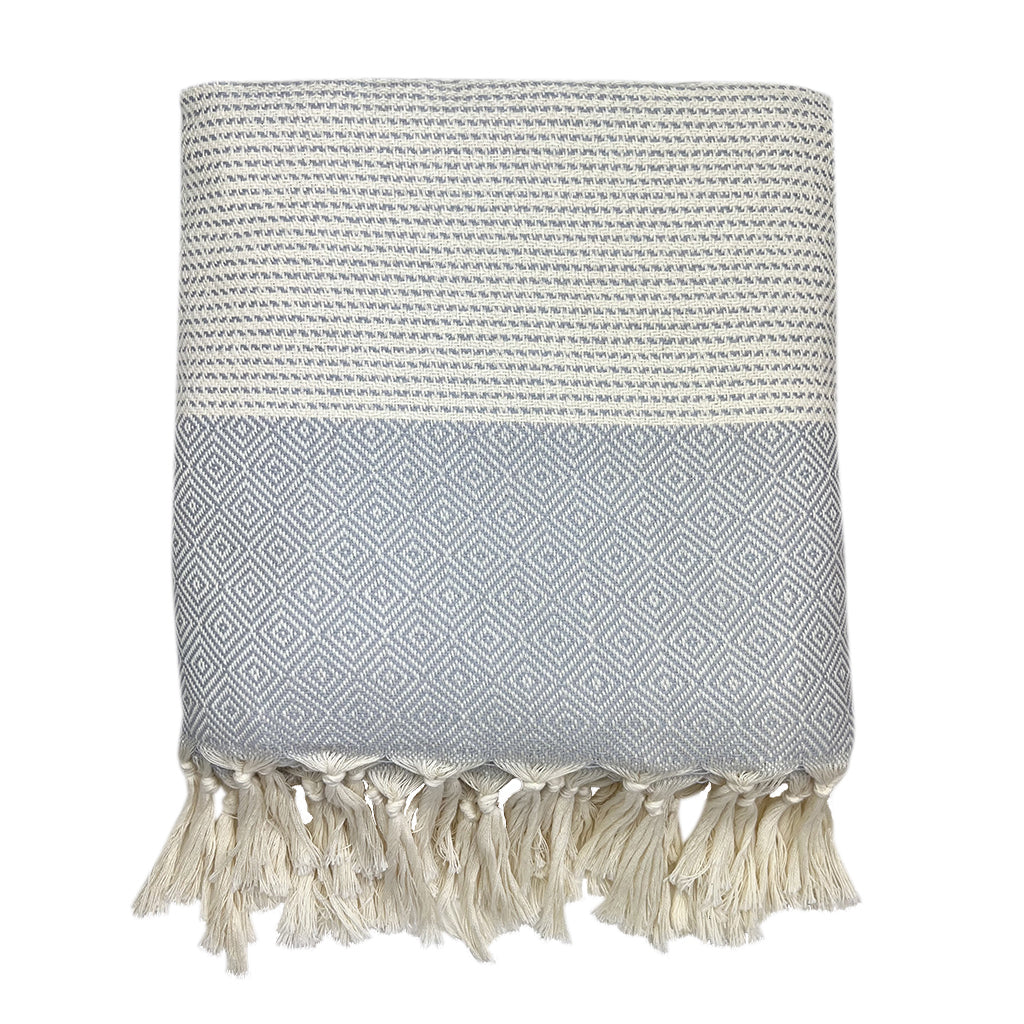 The Diamond Stripe Turkish Throw, in black and white, showcases a geometric diamond pattern and is accented with hand-knotted fringe at the edge, providing both style and comfort.