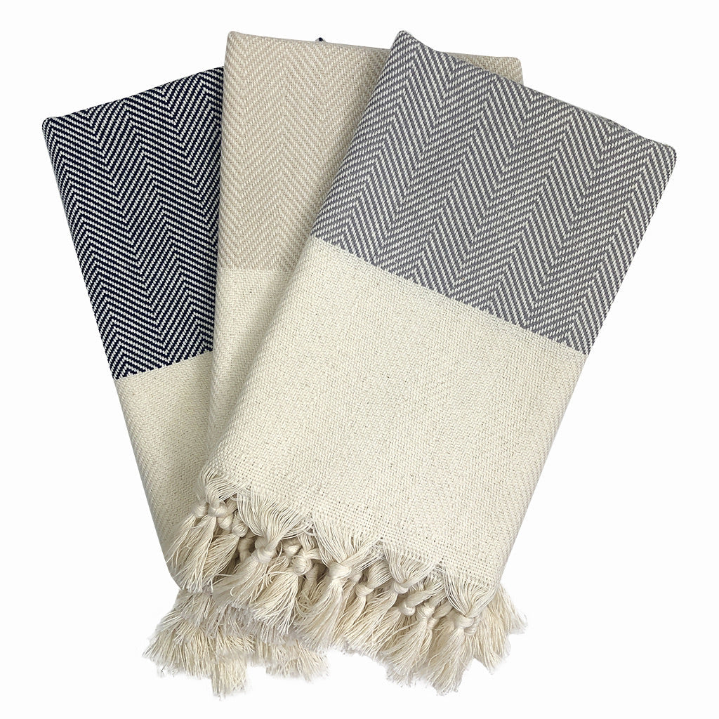 Product: The Herringbone Turkish Hand Towel is crafted from 100% Turkish cotton and displays a blue and white herringbone design, accented with a cream fringe border.
