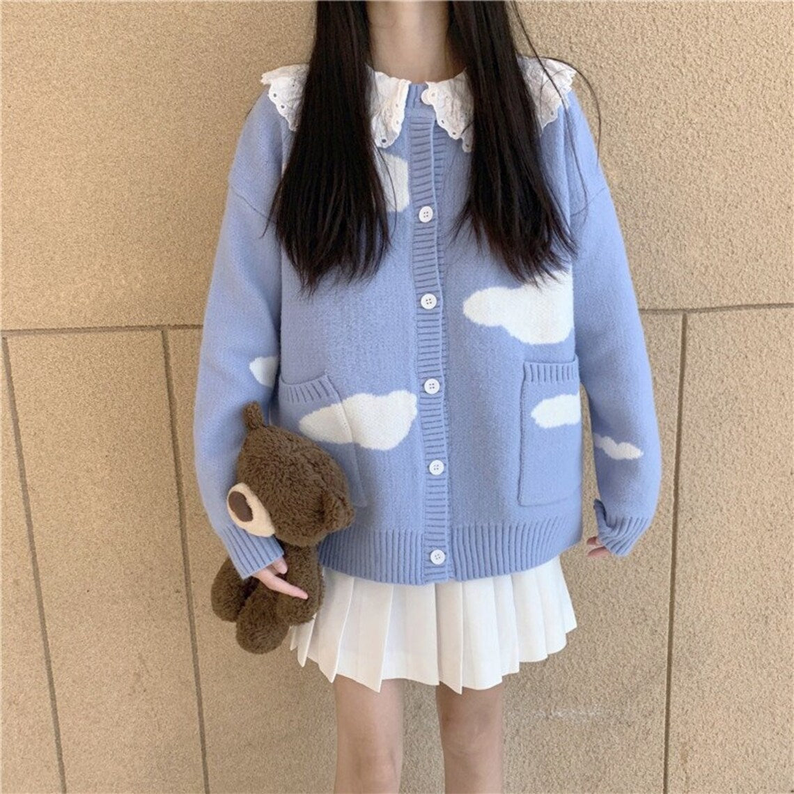 A person in a Kawaii Knitted Clouds Sweatshirt takes a selfie, obscuring their face with a smartphone, featuring Asian size.