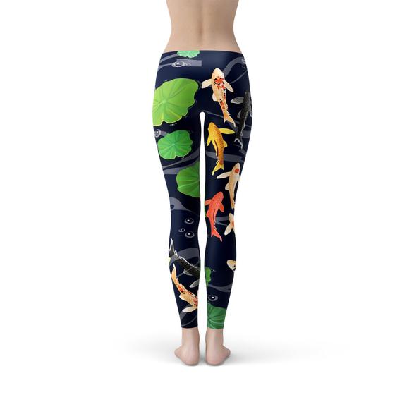 A person is modeling the Womens Koi Fish in Pond Leggings, which feature a koi fish and lily pad pattern on a dark background, crafted from smooth microfiber yarn with four-way stretch for ultimate comfort and flexibility.