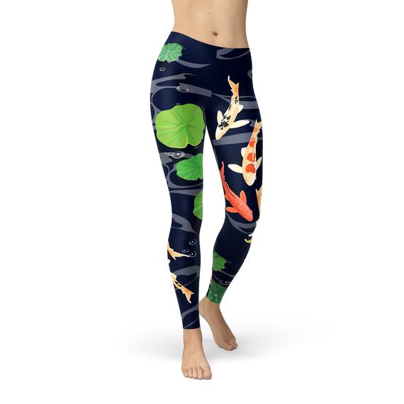 A person is modeling the Womens Koi Fish in Pond Leggings, which feature a koi fish and lily pad pattern on a dark background, crafted from smooth microfiber yarn with four-way stretch for ultimate comfort and flexibility.