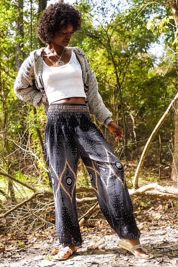 Person wearing a sleeveless black top and Black PEACOCK Women Boho Pants Hippie Pants Yoga Pants with an elastic waist, standing barefoot against a white background. The harem pants are made from 100% Rayon, ensuring both comfort and style.