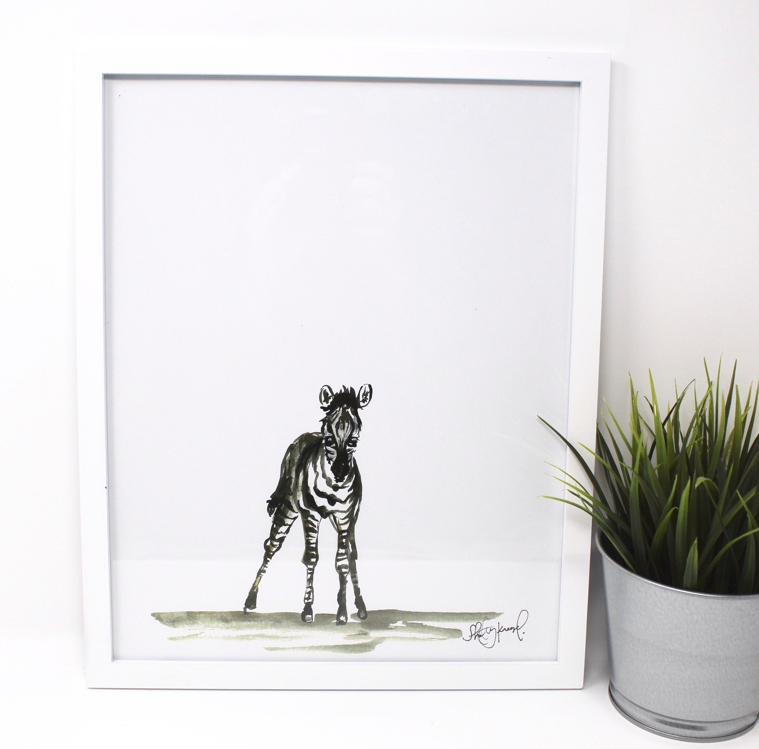 The Baby Zebra Art Print (11x14) is an ideal piece to add charm to a nursery wall or brighten up a baby room with its delightful depiction of a zebra on a blank background. Perfect for those who love animal art, it fits seamlessly into safari-themed home decor and nursery wall art collections.